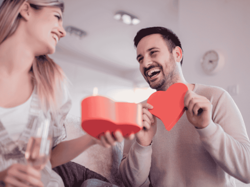 Valentinstags-Date-Box-Ideen, Paar packt Geschenk in Herzform aus.