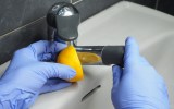 Zitronensäure wird zum Entkalken eines Wasserhahns verwende, indem die Armatur mit einer halben Zitrone eingerieben wird.