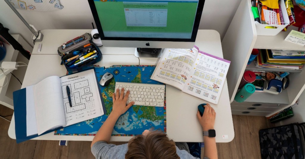 Schreibtisch einrichten Kinderzimmer: ein Junge sitzt an einem Schreibtisch