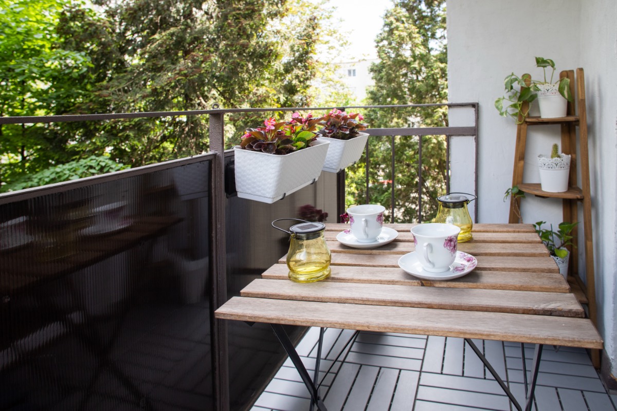Ein schmaler Balkon mit Balkonmöbeln und Pflanzen.