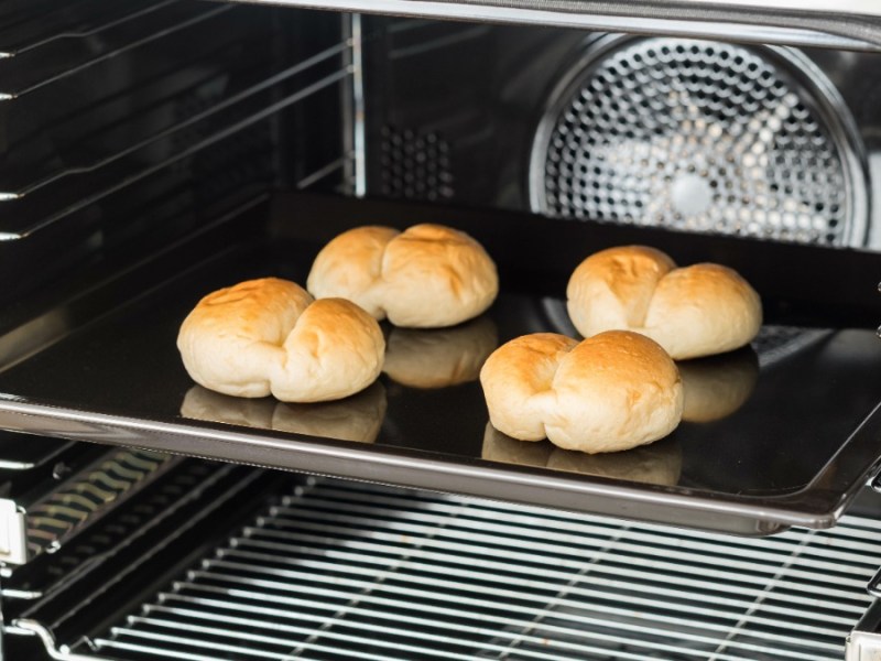 vier Brötchen auf einem Backblech im Ofen