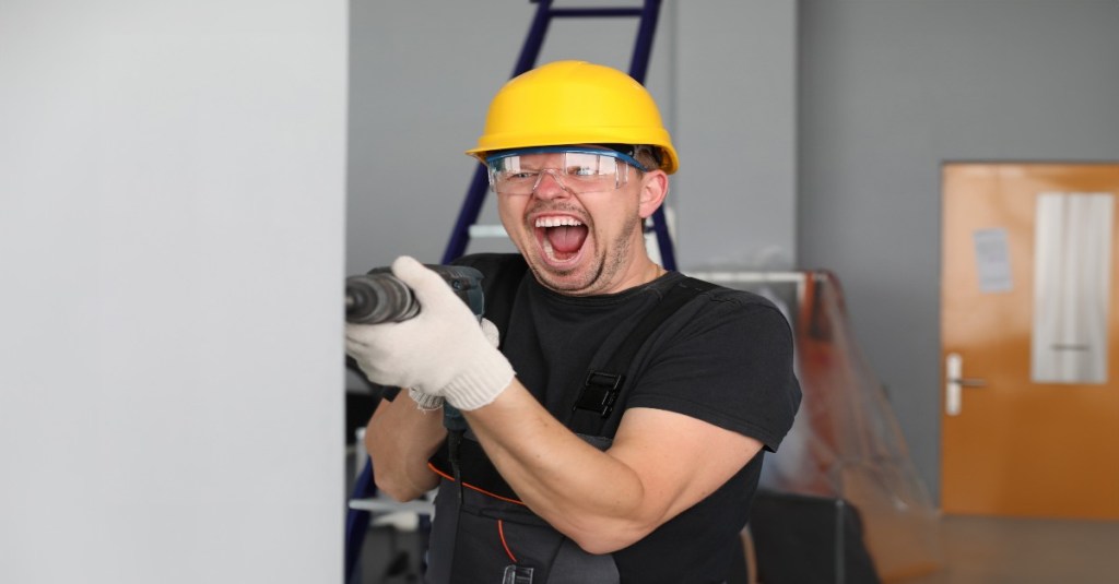 Ein Mann bohrt wütend in eine Wand.