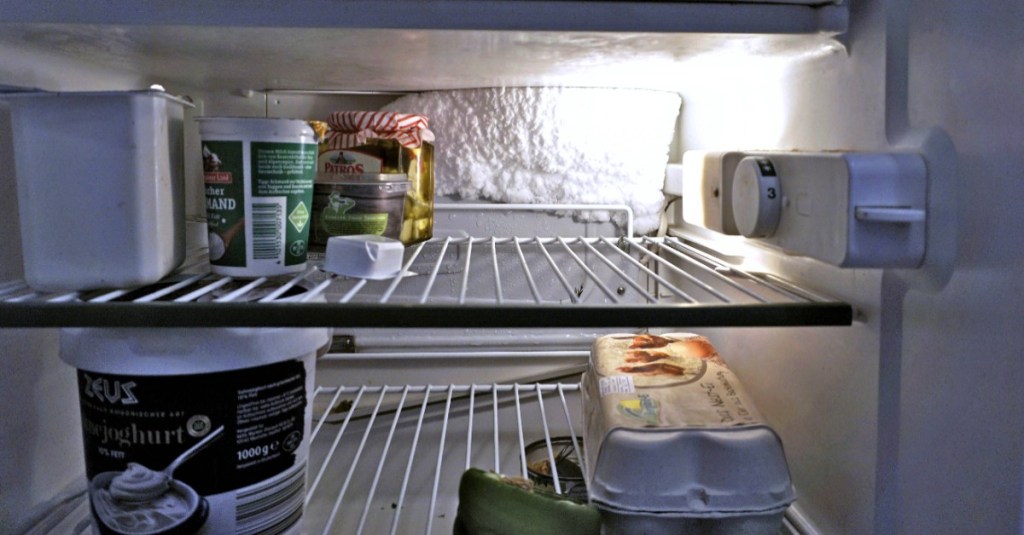 Kühlschrank abtauen: In einem Kühlschrank ist eine dicke Eisschicht an der Rückseite