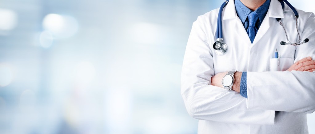 Ein Arzt mit einem Stethoskop, der in einem Krankenhaus steht. 
