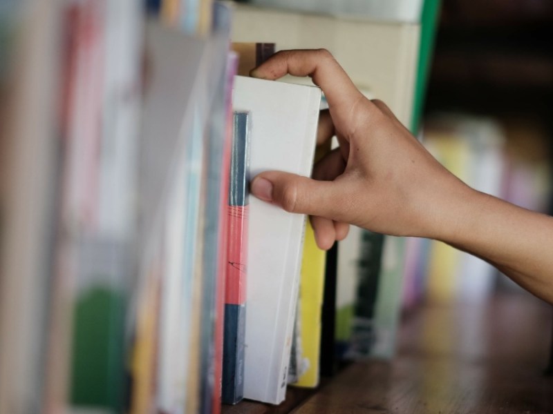 jemand nimmt ein Buch aus einem Bücherregal