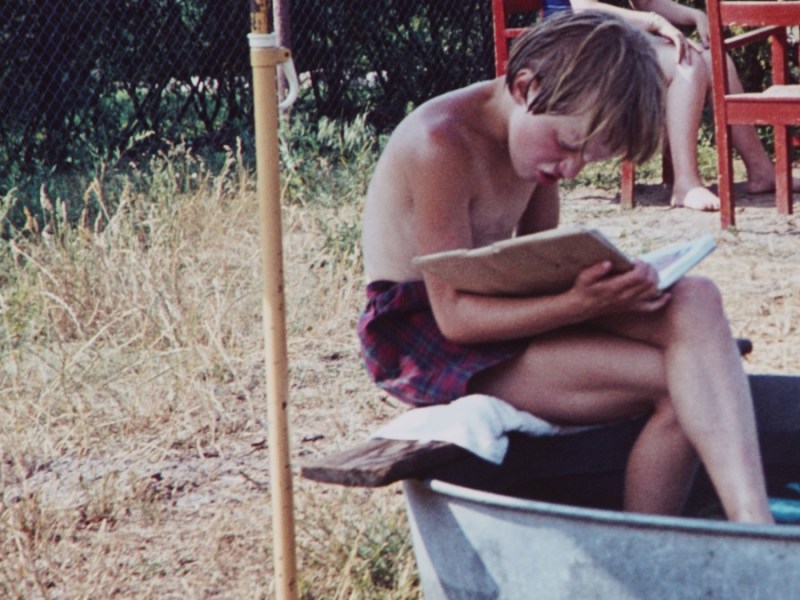 Aufnahme eines Jungen im Jahr 1960, der ein Buch liest, während er auf dem Rand einer Zinnwanne sitzt