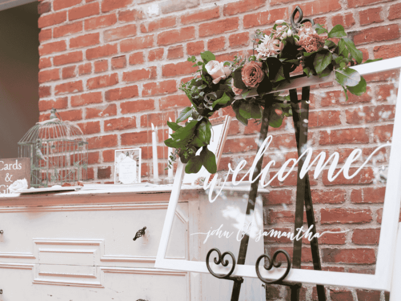Willkommensschild Hochzeit, weißer Rahmen mit Glasscheibe und Blumendeko